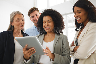 Buy stock photo Group of happy diverse businesspeople standing and using a digital tablet together in an office. Content business professionals working and planning on a digital tablet at work