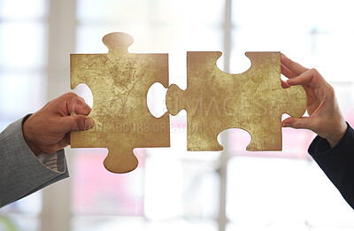 Buy stock photo Two businesspeople holding and fitting puzzle pieces together in an office at work. Business professionals solving a jigsaw problem