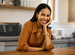 Young happy beautiful mixed race woman enjoying a relaxing day alone at home. Confident hispanic female in her 20s smiling while relaxing in the kitchen at home