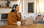 Young happy mixed race businesswoman talking while on a virtual meeting using a laptop at home. One hispanic female businessperson talking and wearing headphones while on a call using a laptop
