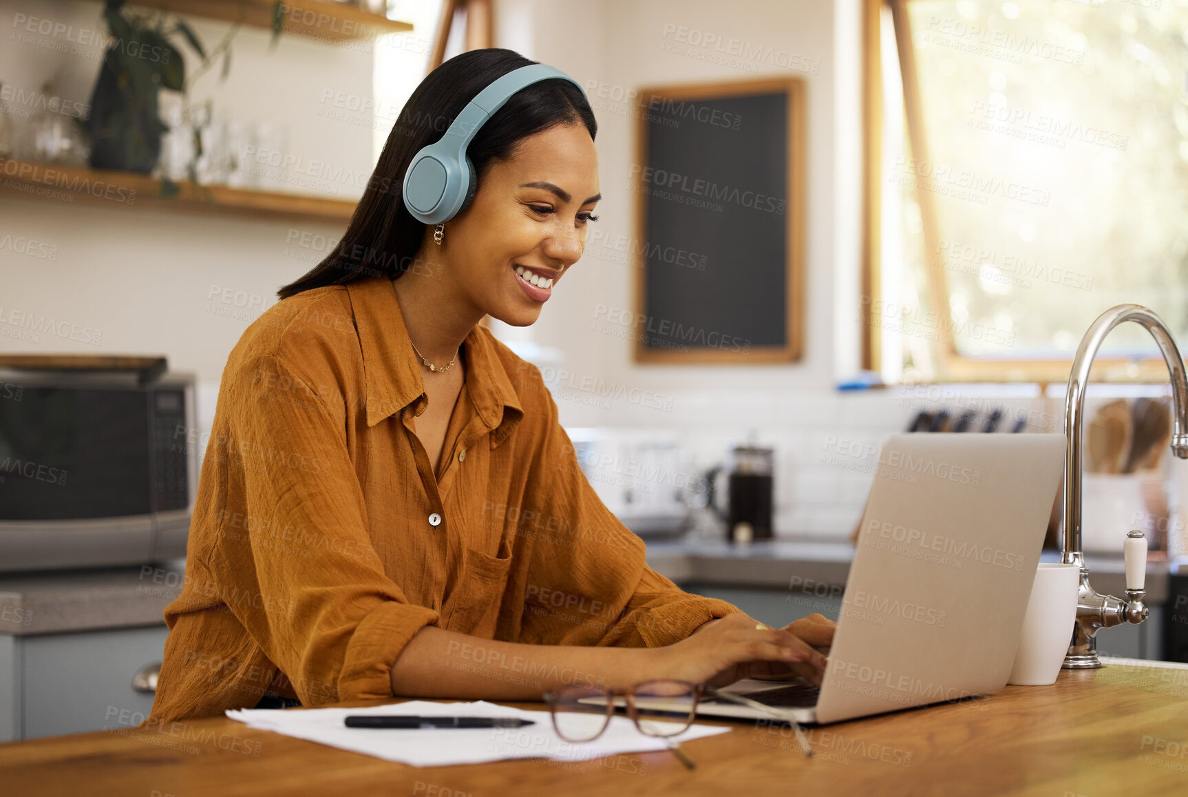 Buy stock photo Typing, remote work and woman on laptop happy at home working on project, strategy and planning in kitchen. Freelancer, business and girl with headphones for music, working online and streaming audio
