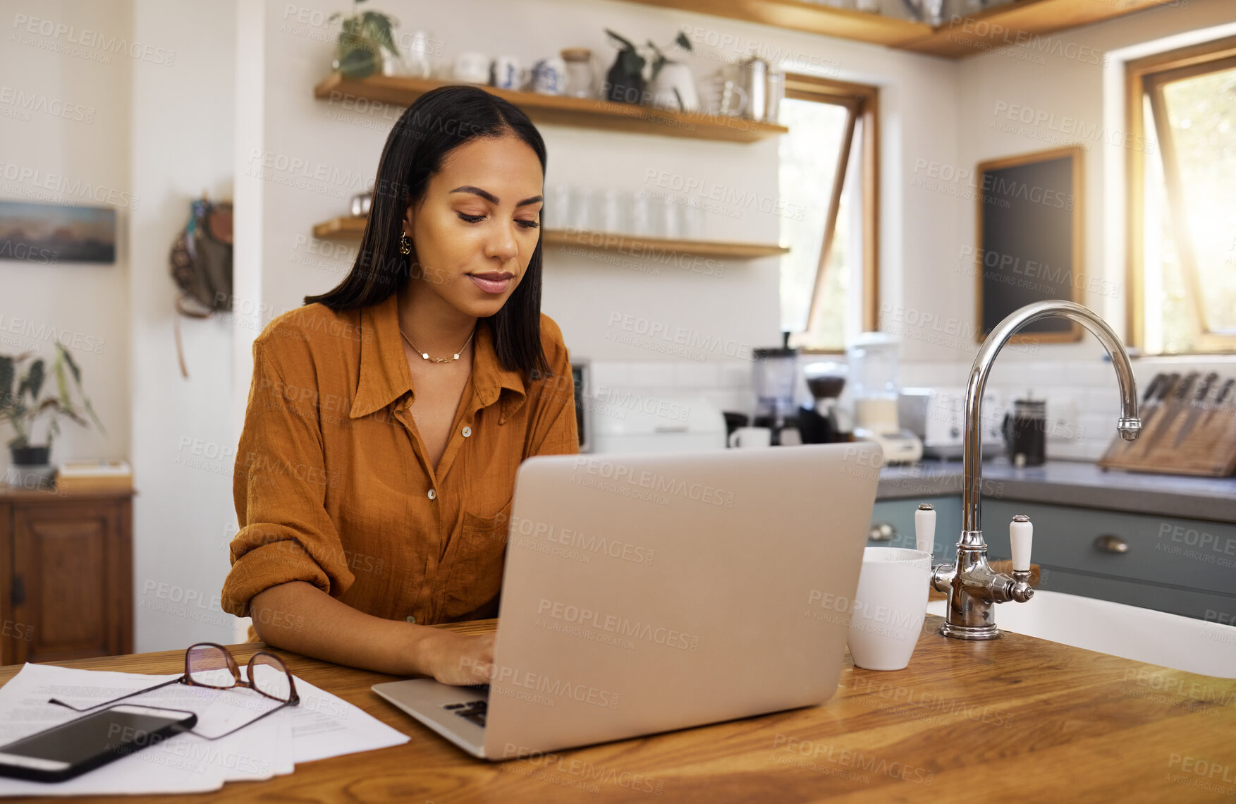 Buy stock photo Home, remote work and business woman on laptop for research project, strategy and planning in kitchen. Freelancer, focus and girl with documents working online, typing email and busy on computer