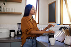 Young beautiful serious mixed race woman making herself some coffee in the morning. Content hispanic female in her 20s preparing coffee alone in the kitchen at home