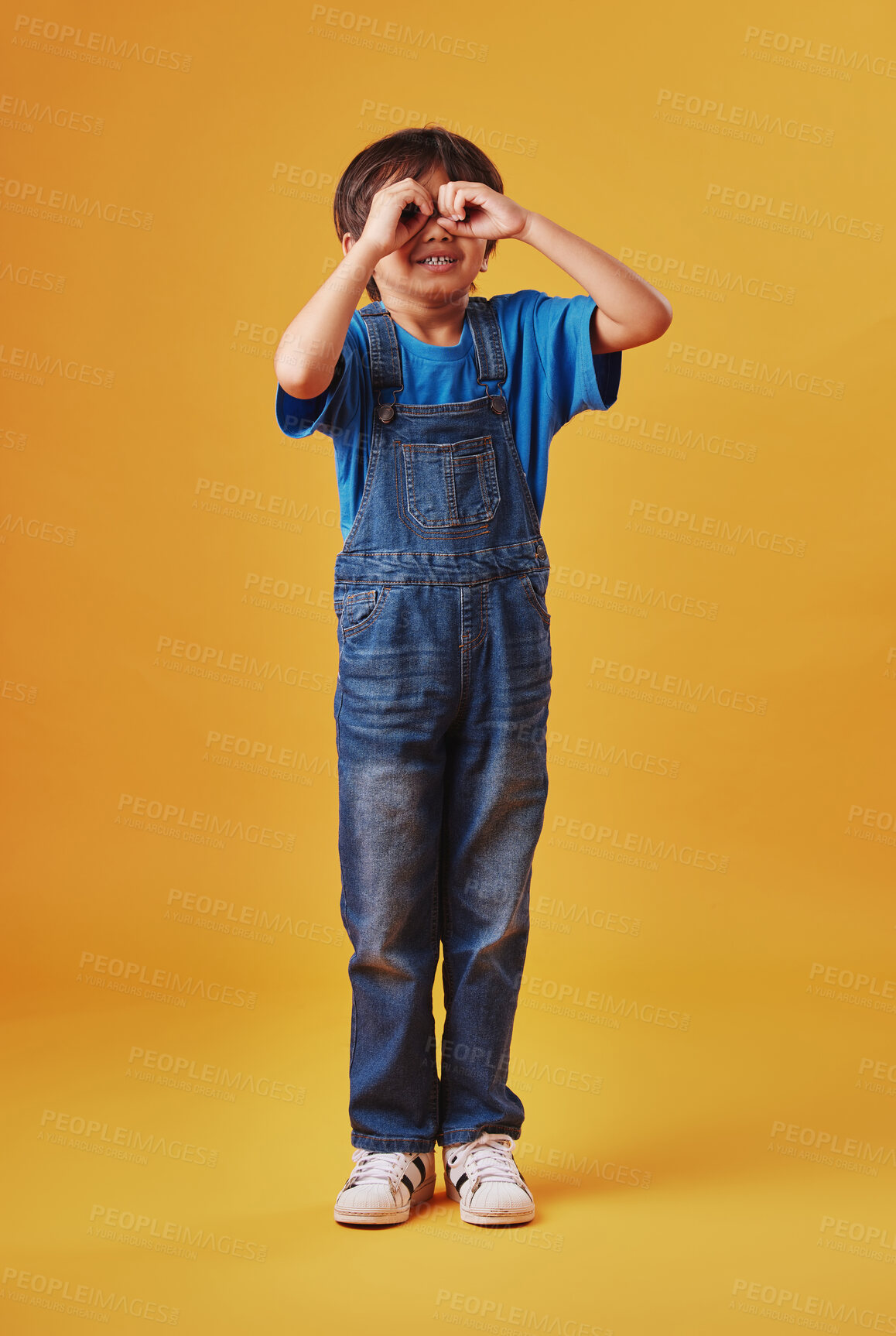 Buy stock photo Happy, hand binoculars and child in studio for imagination, playing and adventure with fantasy. Smile, youth and boy kid with goggles for vision game, discovery or spy search by yellow background.