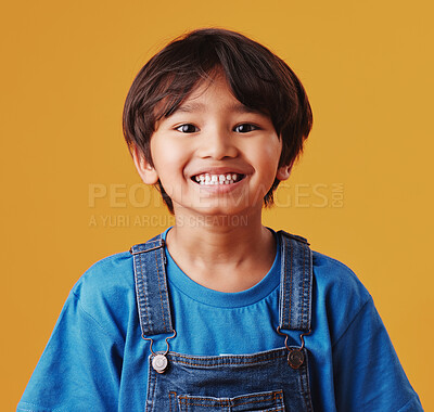 Portrait of a cute little asian boy wearing casual clothes while smiling and looking excited. Child standing against an orange studio background. Adorable happy little boy safe and alone