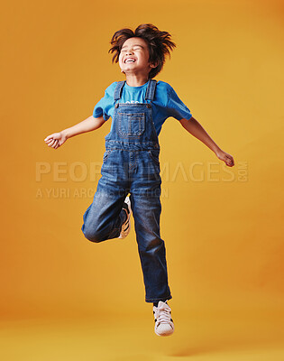 One cute mixed race child wearing casual clothes while having fun and being energetic against an orange copyspace background. Asian kid being active