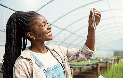 Buy stock photo Botanist looking at a plant sample. Young farmer holding a test tube sample. Farmer holding chemistry plant sample. Happy farmer looking at research plant sample. Farmer working in botany.