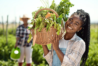 Buy stock photo farmer working with organic produce on a farm. Portrait of a farmer holding a basket of produce. Young farmer holding a basket of harvested vegetables. Happy farmer standing in a garden