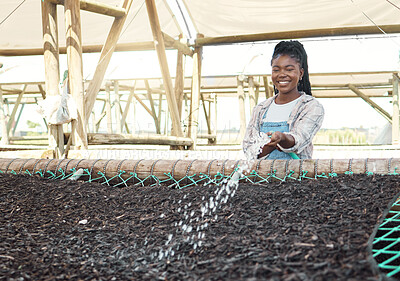 Buy stock photo Happy farmer watering a bed of soil. Young farmer watering a bed of dirt. Farmer watering plants with a hose. Smiling farm worker watering soil. Farmer working to conserve dirt