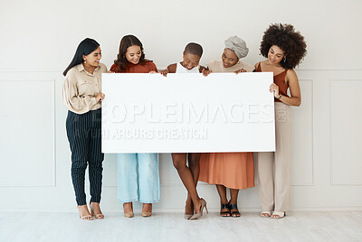 Group of five diverse young businesswomen standing against a wall in an office and holding a blank sign. Happy colleagues holding a sign with a message while standing in a row together at work
