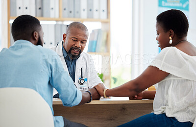 Buy stock photo Doctor, black couple and holding hands in consultation clinic, support and comfort. Healthcare, obstetrician and man and woman talking with medical professional for advice, fertility treatment or ivf