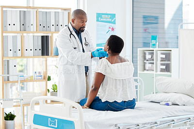 Doctor feeling a patients neck. Mature doctor in a consult with a patient. African american doctor checking the throat of a patient. Caring medical gp and a patient in a consult.