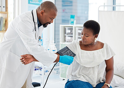 Mature doctor checking the blood pressure of a patient. African american doctor applying blood pressure cuff. Medical employee in a consult with the doctor. Healthcare gp monitoring blood pressure