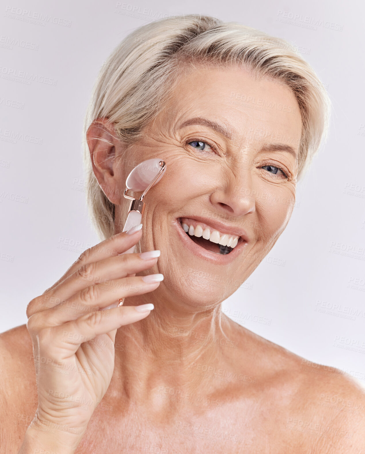 Buy stock photo Mature, portrait and woman using rose roller on face for skincare massage and beauty spa routine. Feminine, selfcare and cosmetics for anti ageing facial treatment with white studio background.
