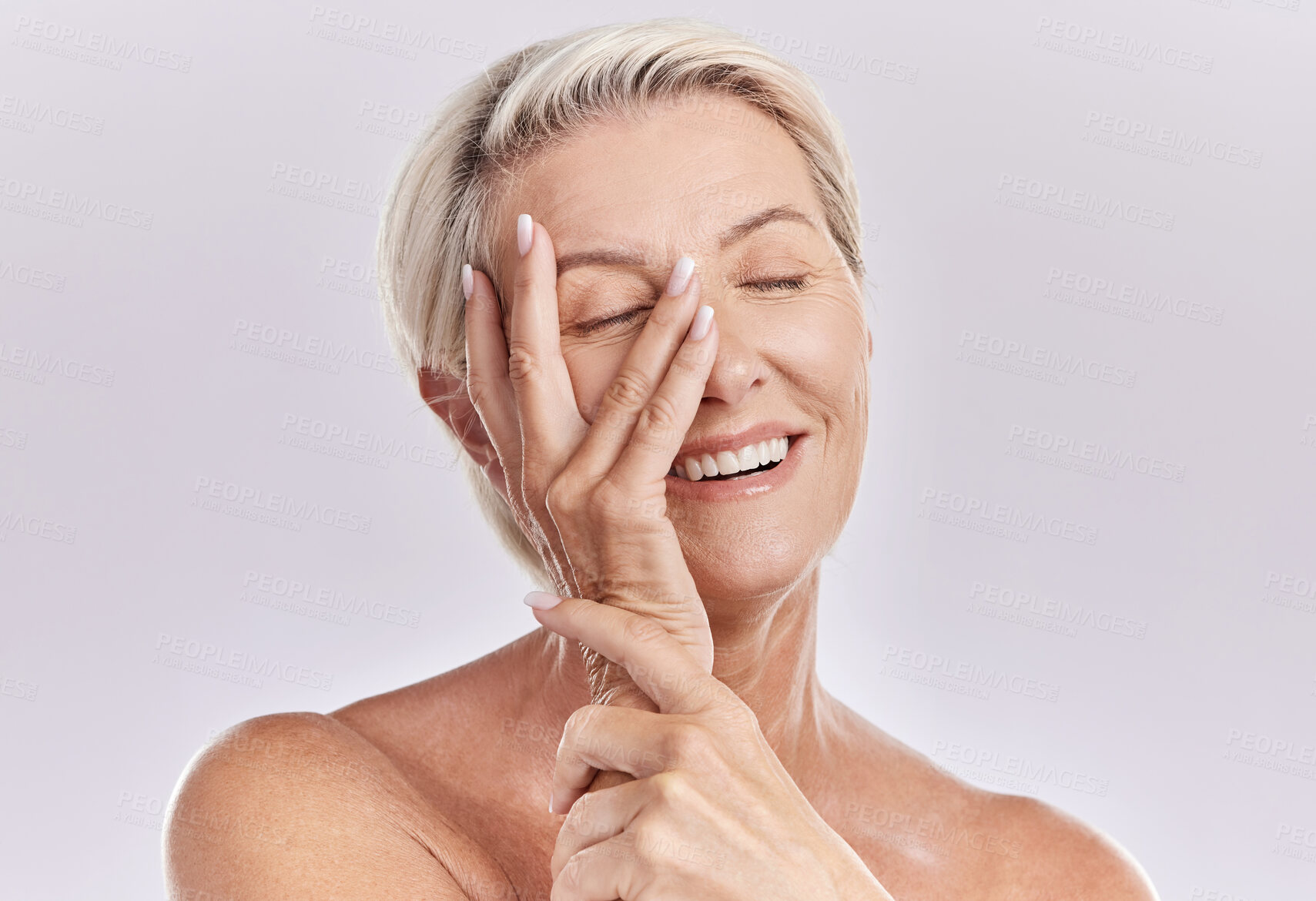 Buy stock photo Skincare, wellness and beauty with a senior woman touching her smooth skin and beautiful face with her hand in studio on a grey background. Natural, health and skin care with a female feeling happy