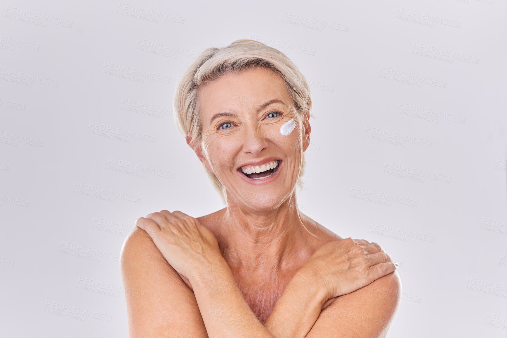 Buy stock photo Smile in portrait, old woman and cream on face, beauty with antiaging skincare and dermatology on white background. Sunscreen, moisturizer and female model, lotion and skin glow with facial in studio