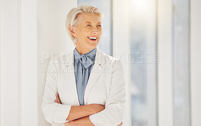 Confident mature caucasian businesswoman standing with her arms crossed in an office alone. One female only with grey hair looking thoughtful while smiling and laughing. Ambitious entrepreneur and determined leader daydreaming about success in her startup