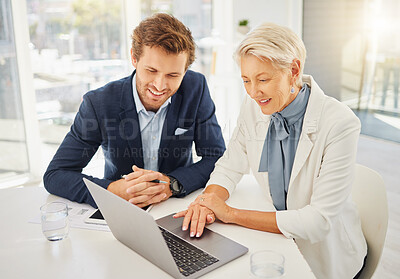 Two smiling caucasian colleagues from above working together on a laptop in an office boardroom. Young businessman and mature businesswoman planning online while browsing the internet for ideas and inspiration