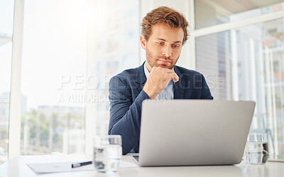 One focused young caucasian businessman thinking with hand on chin while working on a laptop in an office. Ambitious male entrepreneur planning and considering decisions while browsing the internet. Man listening to a virtual conference via webcam