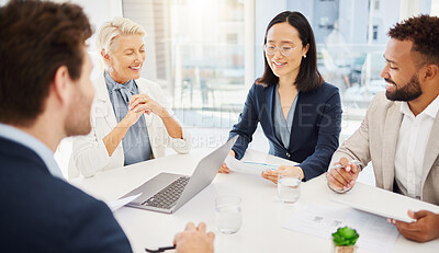 Confident young asian businesswoman explaining plans and ideas to her diverse colleagues while going through paperwork during a meeting in an office boardroom. Happy businesspeople having a discussion while brainstorming together