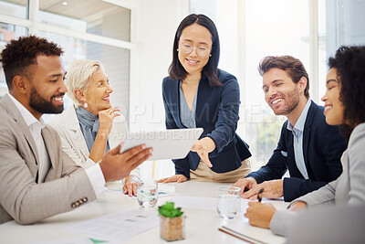 Confident young asian businesswoman leading a presentation with her diverse colleagues during a meeting in an office boardroom. Happy businesspeople browsing on digital tablet device while planning a strategy together