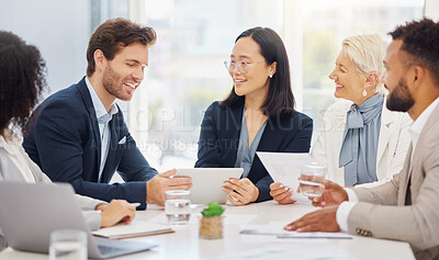 Happy young diverse colleagues discussing plans and ideas together on a digital tablet device during a meeting in an office boardroom. Asian businesswoman and caucasian businessman brainstorming online while presenting feedback to their team