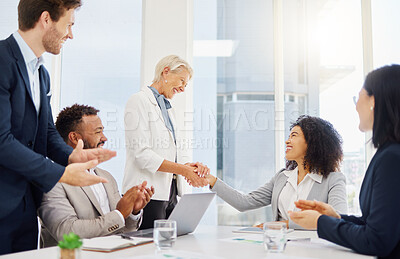 Smiling mature caucasian manager and mixed race businesswoman shaking hands during a meeting in an office boardroom. Diverse businesspeople cheering and clapping hands while feeling inspired after a successful promotion, corporate deal and merger