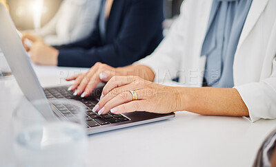 Closeup of caucasian businesswoman typing on a laptop keyboard in an office. Hands of woman pressing buttons to send email and browse the internet while brainstorming alongside a colleague