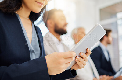 Closeup of businesswoman browsing on a digital tablet device during a presentation in an office boardroom with her diverse colleagues. Hands of woman searching online and taking digital notes while sitting in the audience during a conference