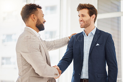 Smiling young caucasian businessman shaking hands with a colleague in an office. Two executives greeting and saying congratulations for a promotion, corporate deal or merger