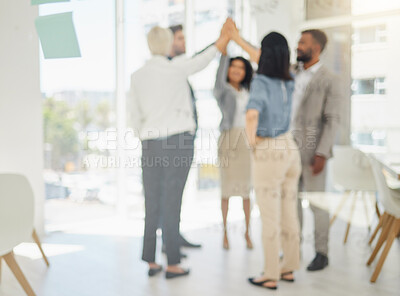 Defocused shot of diverse businesspeople giving each other a high five while standing together in a huddle in an office. Blurred shot of ambitious colleagues staying motivated and inspired. Staff celebrating success and achievement as a united team