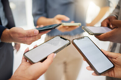Closeup of diverse group of businesspeople using cellphones with blank screens in synchronicity while standing in a circle around each other. Colleagues browsing online and searching the internet in a huddle. Downloading and sharing media together