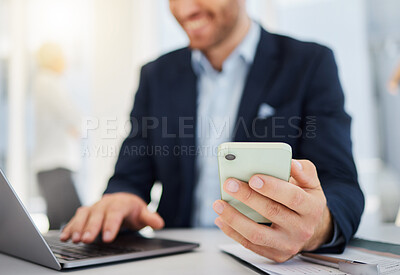 Closeup of one caucasian businessman browsing on a laptop and sending texts on a cellphone in an office. Hands of entrepreneur planning and doing banking on his digital wireless devices