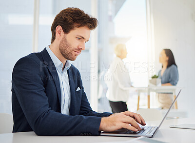 Focused young caucasian businessman typing on a laptop keyboard in an office. Dedicated entrepreneur browsing online while completing deadlines and sending emails
