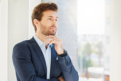 One focused young caucasian businessman thinking with hand on chin in an office. Ambitious entrepreneur daydreaming about success in his startup