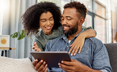 Buy stock photo Mixed race couple smiling while using a digital tablet together at home. Cheerful hispanic boyfriend and girlfriend relaxing and using social media on a digital tablet in the lounge at home