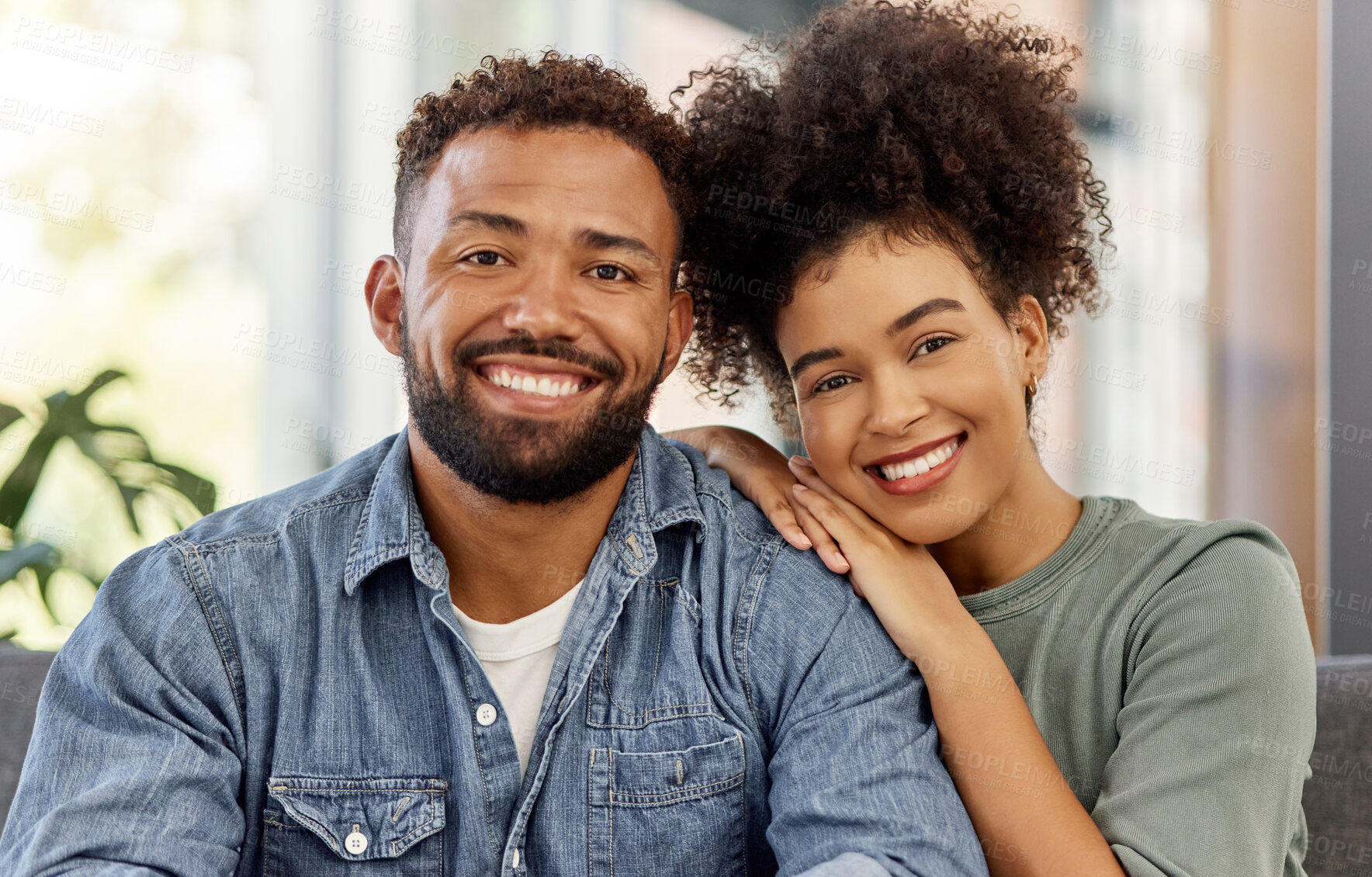 Buy stock photo Portrait of a happy mixed race couple smiling while relaxing together at home. Carefree hispanic husband and wife bonding together in the lounge at home