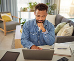 Freelance businessman reading an email on his laptop. Remote virtual worker thinking while typing on his computer. Young businessman using a wireless digital device at home