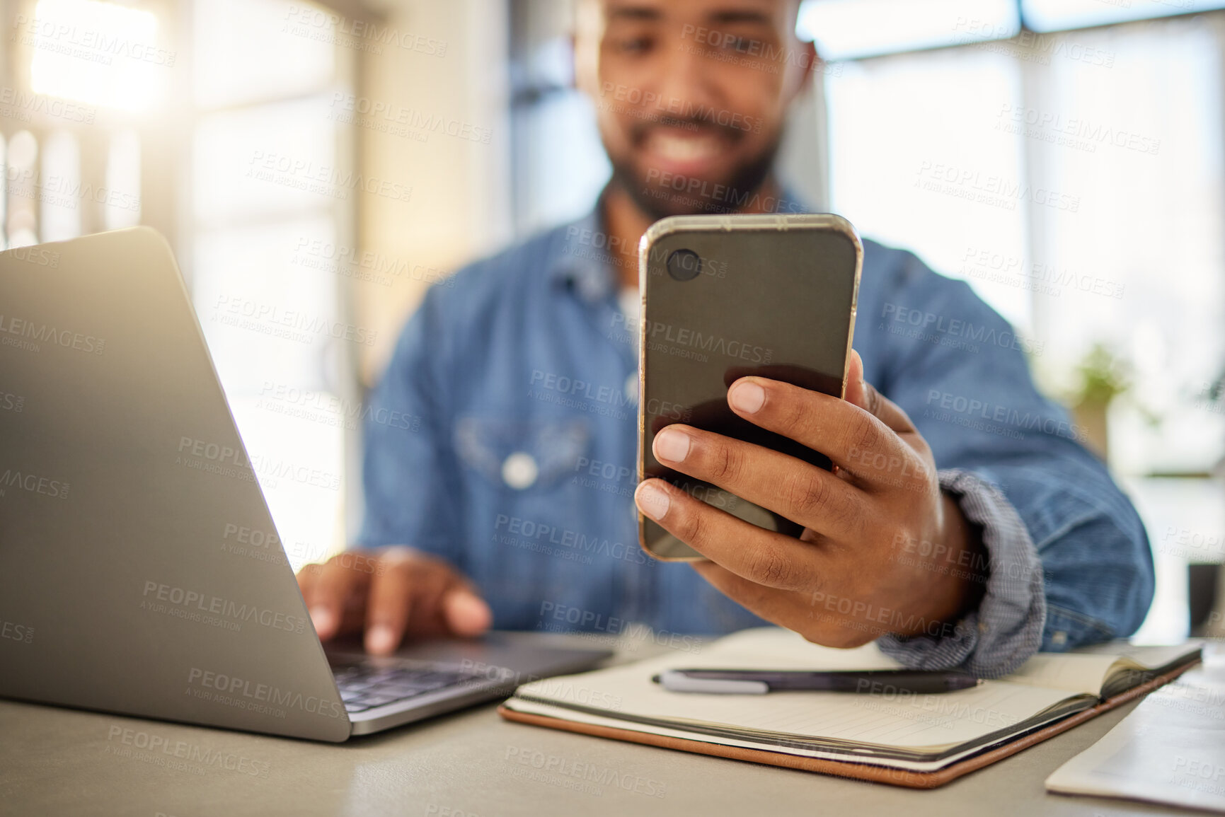 Buy stock photo Businessman sending a text message on his smartphone at home. Young entrepreneur using his cellphone to read a message. Always online with his wireless device. Keeping connected to the internet