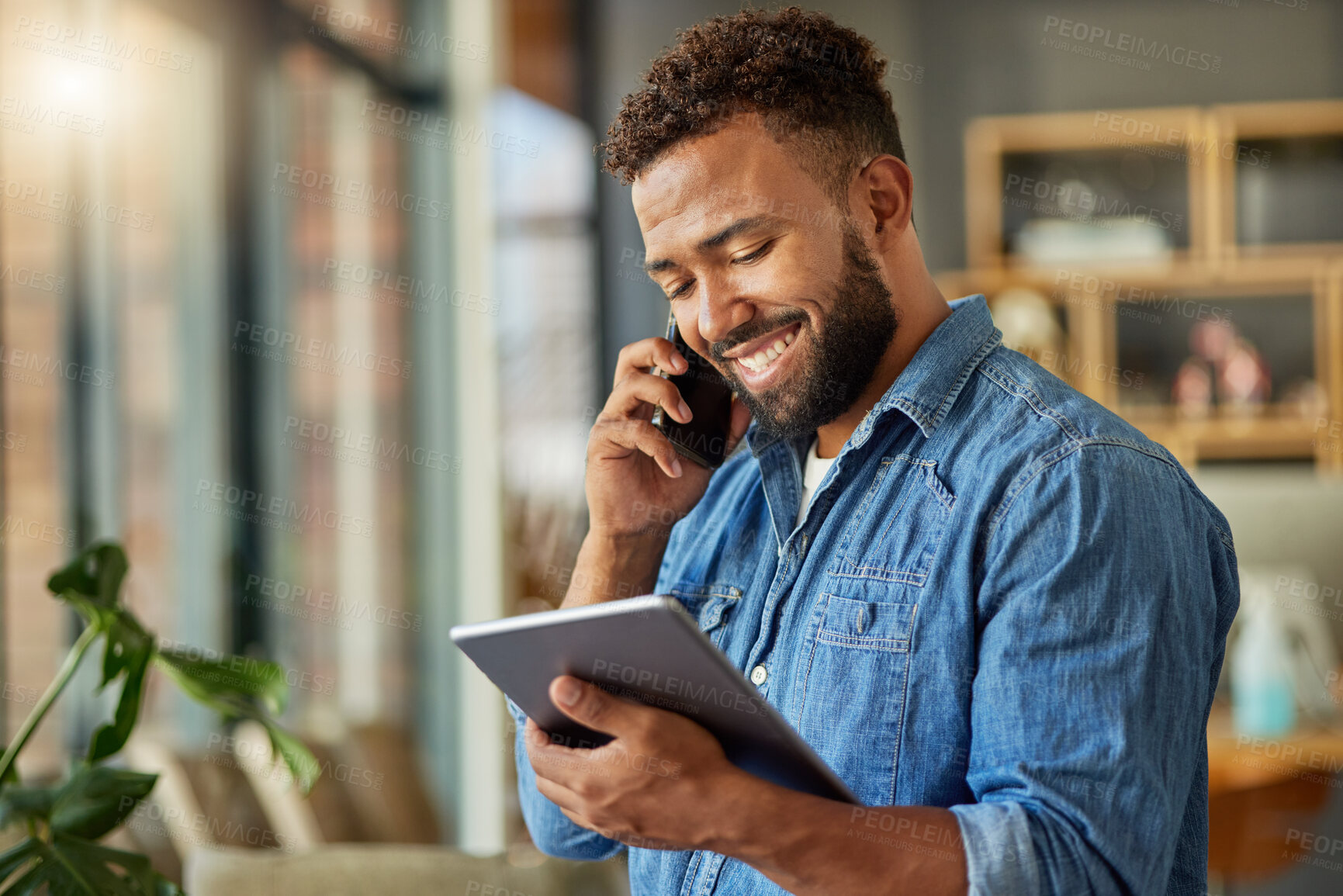 Buy stock photo Businessman reading an email on his digital tablet. Young freelance entrepreneur making s call on his cellphone at home. Hispanic businessman working on his wireless device at home