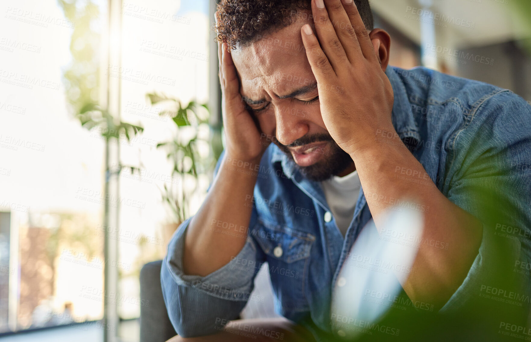 Buy stock photo Young man with a headache at home. Young bachelor with a migraine in his apartment.Stressed young man in his lounge. Young man suffering with anxiety having a breakdown crisis alone