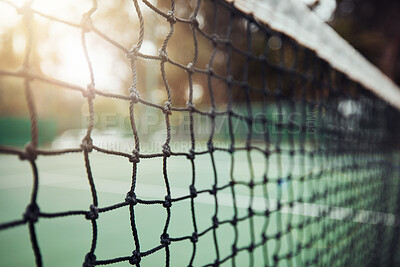 Closeup of a tennis net on an empty court after a game during the day. Still life net with texture and detail after a competitive sports match in a sports club. Nobody playing tennis and lens flare
