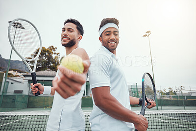 Buy stock photo Two ethnic tennis players holding ball as invite to play court game. Smiling ethnic athletes team standing back to back. Challenge to play competitive sports doubles for healthy fitness in sports club