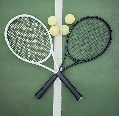 Above view of two tennis rackets and balls on an empty court in a sports club. Aerial view of black and white tennis gear and equipment on asphalt. Ready to play a competitive game versus an opponent