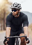 Fit and active indian man wearing a helmet and sunglasses to cycle outdoors for a workout. Focused mixed race athlete exercising with a bicycle. Hispanic routine training, physical activity, healthy