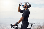 Hispanic athletic man taking a break from cycling to drink water from a bottle. Fit young man drinking water while standing outside with his bike. Active man drinking water from his bottle