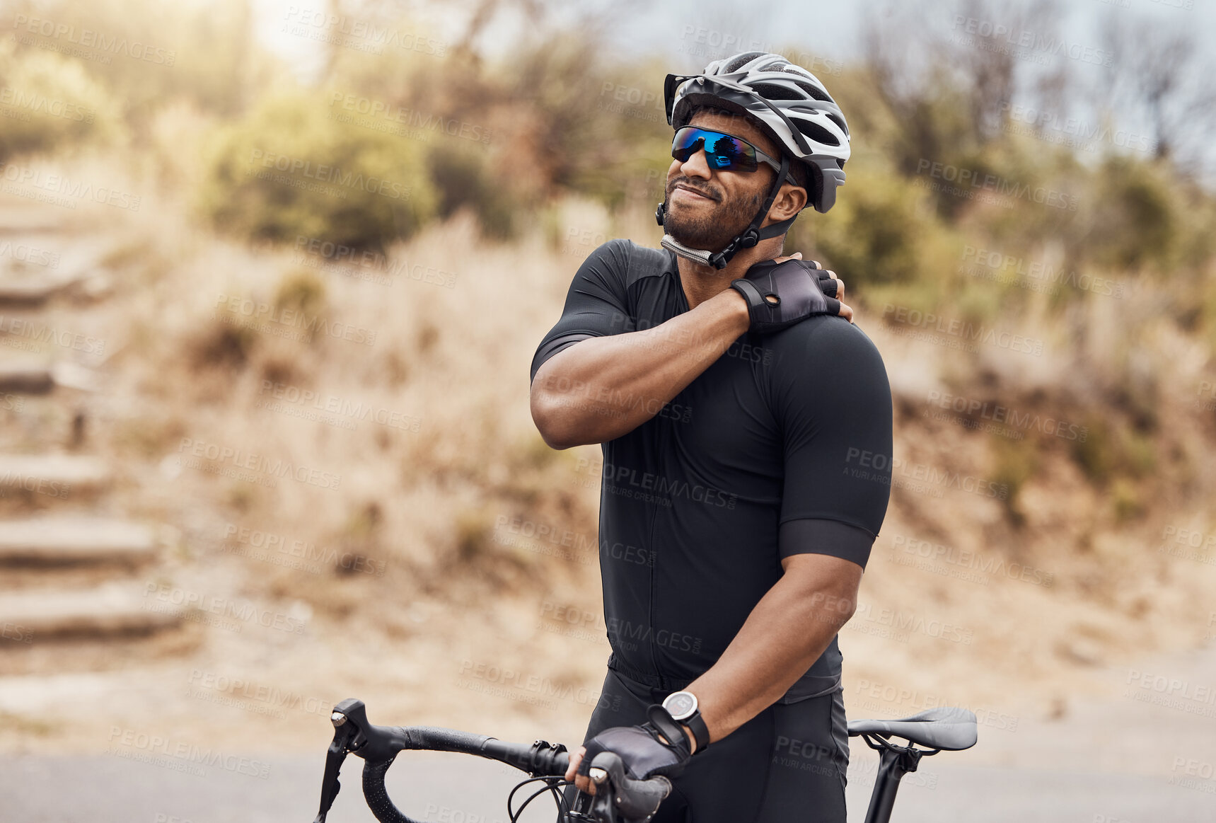 Buy stock photo Fit hispanic young man touching his shoulder, experiencing a cramp. Young man taking a break from cycling for a neck and shoulder injury. Athletic man standing outside with his bike

