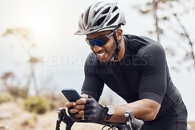 Buy stock photo Smiling male cyclist using his smartphone while sitting on his bike. Fit sportsman smiling and using mobile phone while cycling outdoors