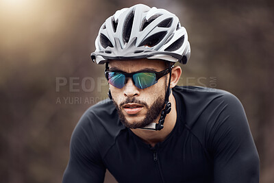Buy stock photo Closeup of one athletic young man cycling outside. Serious guy wearing helmet and glasses while riding a bike for exercise or competition race. Endurance and cardio during a workout and training