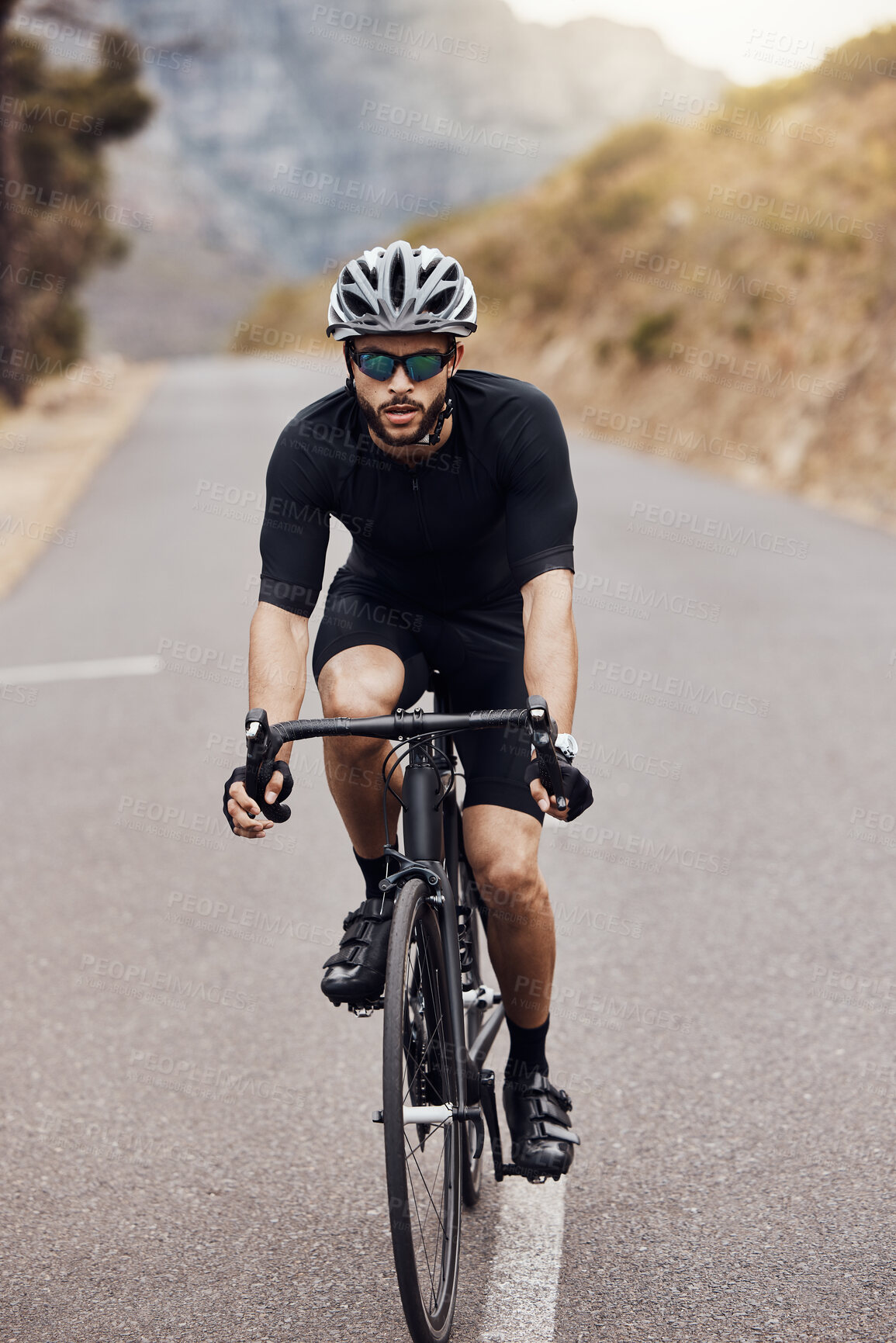 Buy stock photo Athletic male cyclist wearing glasses and a helmet. Sporty fit male Wearing his fitness gear while riding a bike on a road along the mountain for exercise